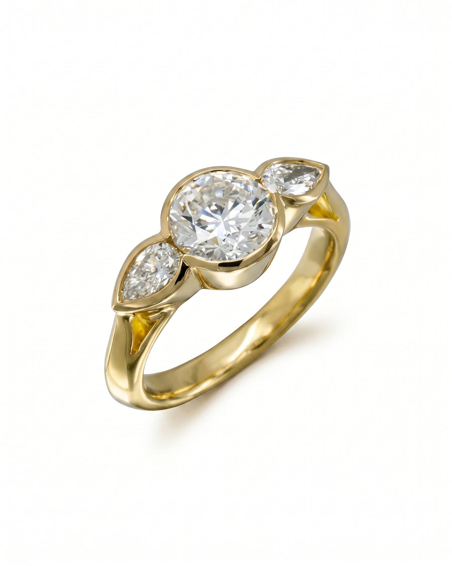 Gold engagement ring with a round brilliant and two pear shaped diamonds.