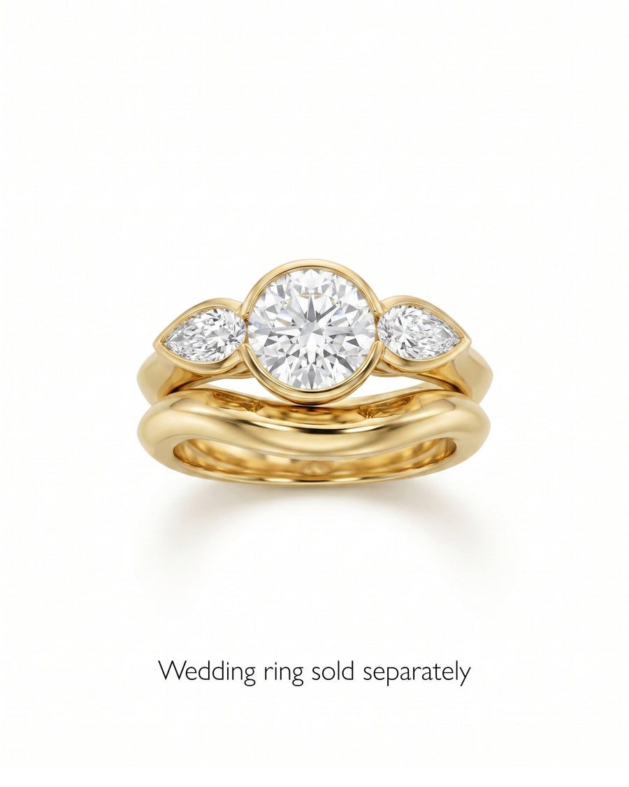 Gold engagement ring with a round brilliant and two pear-shaped diamonds.