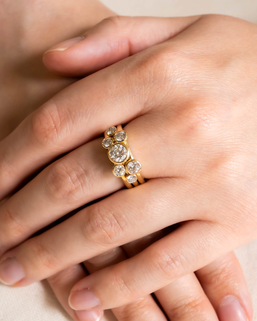 Yellow gold stacking rings with round brilliant diamonds on a hand.