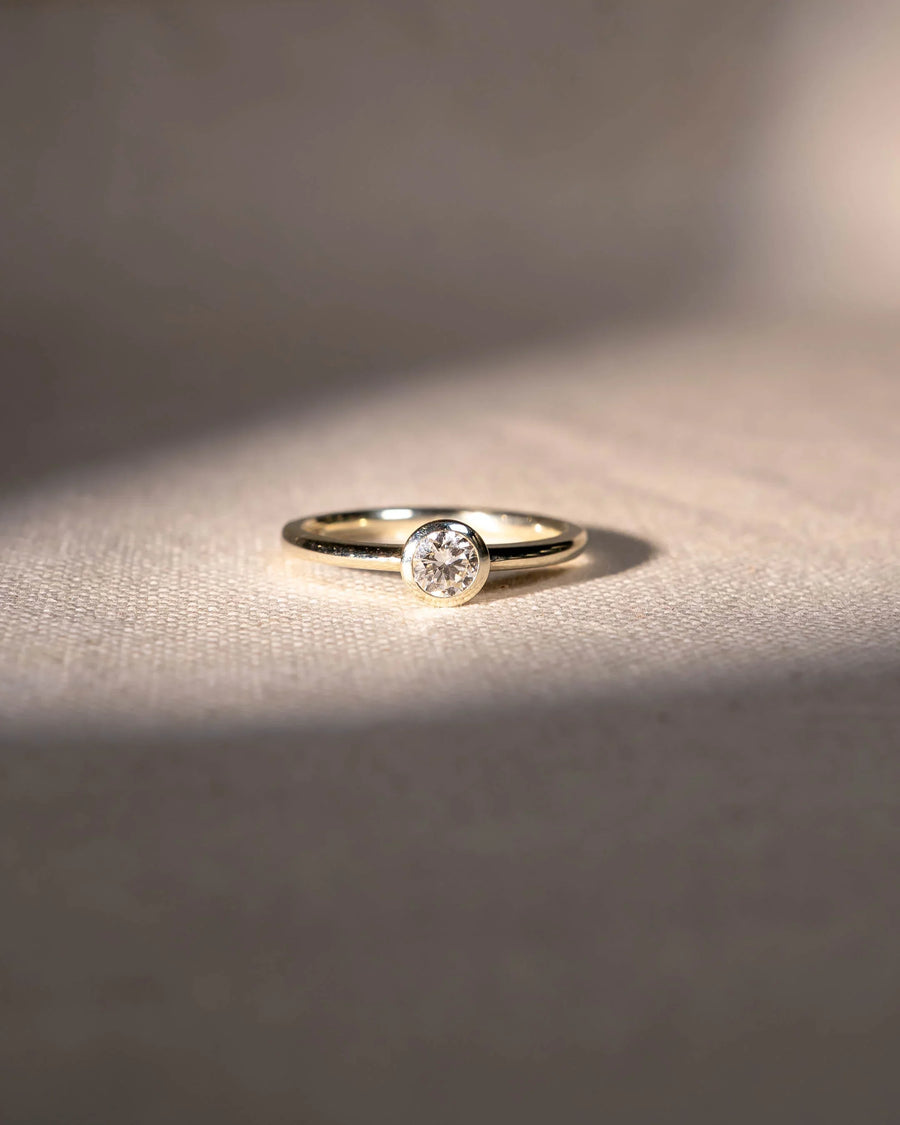 Yellow gold engagement ring with a round cut natural diamond in a bezel setting.