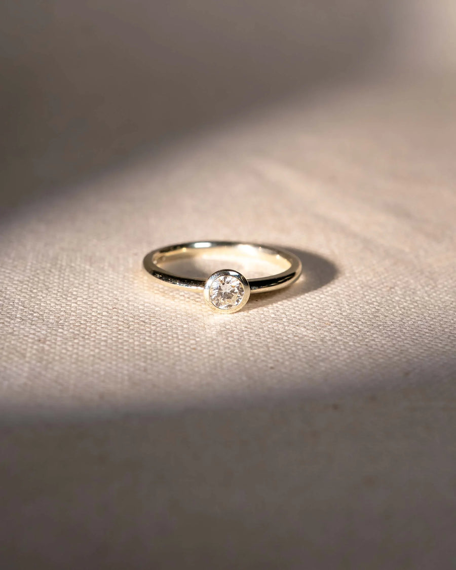 Yellow gold engagement ring with a round cut natural diamond in a bezel setting.