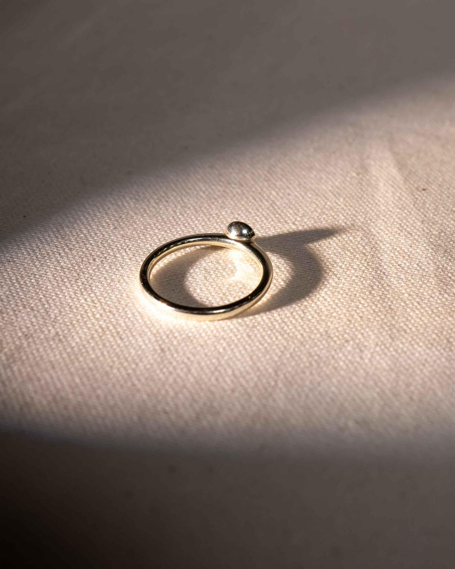 Silver ring with a small round diamond in a bezel setting.