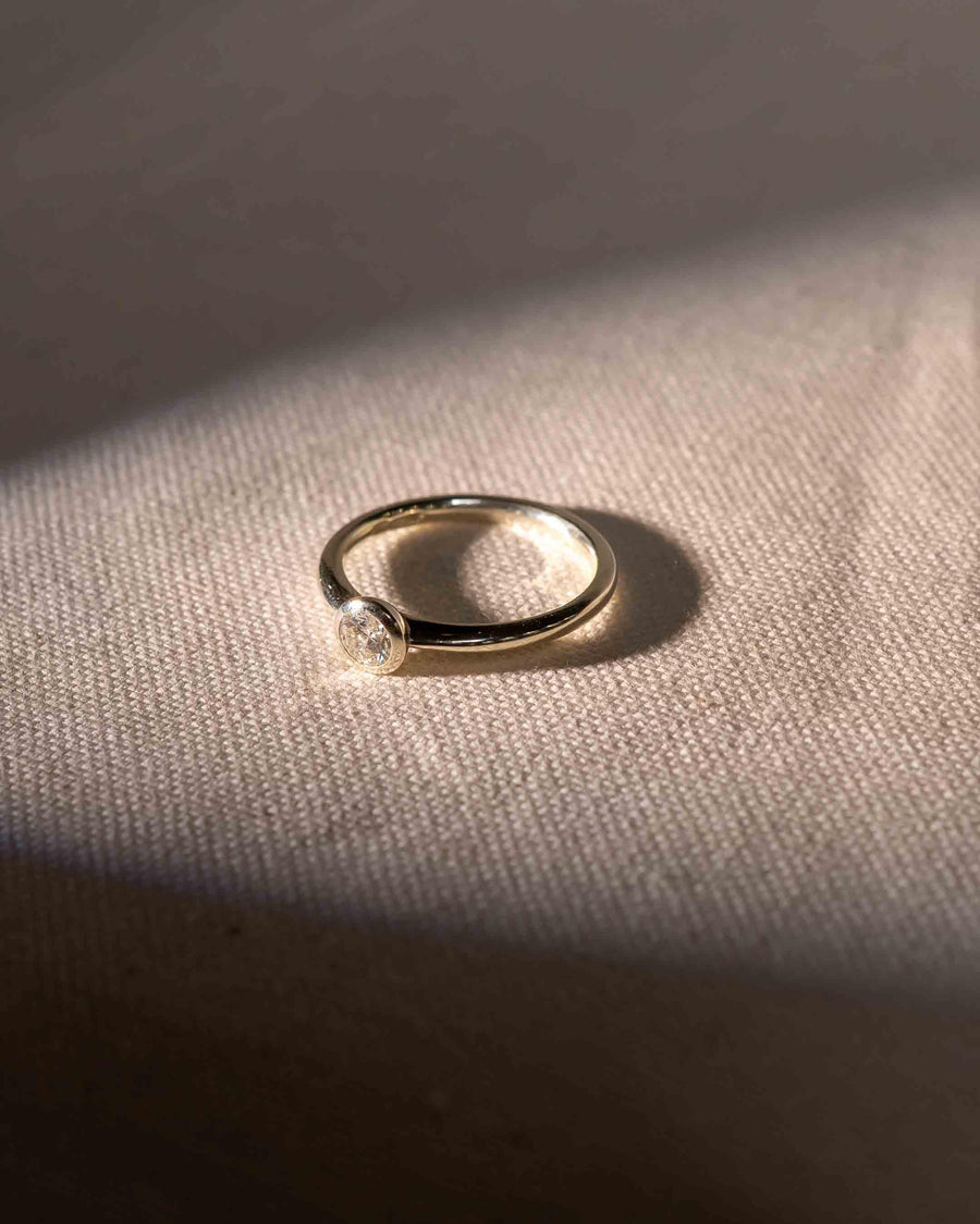 Yellow gold engagement ring with a round cut natural diamond in a bezel setting.
