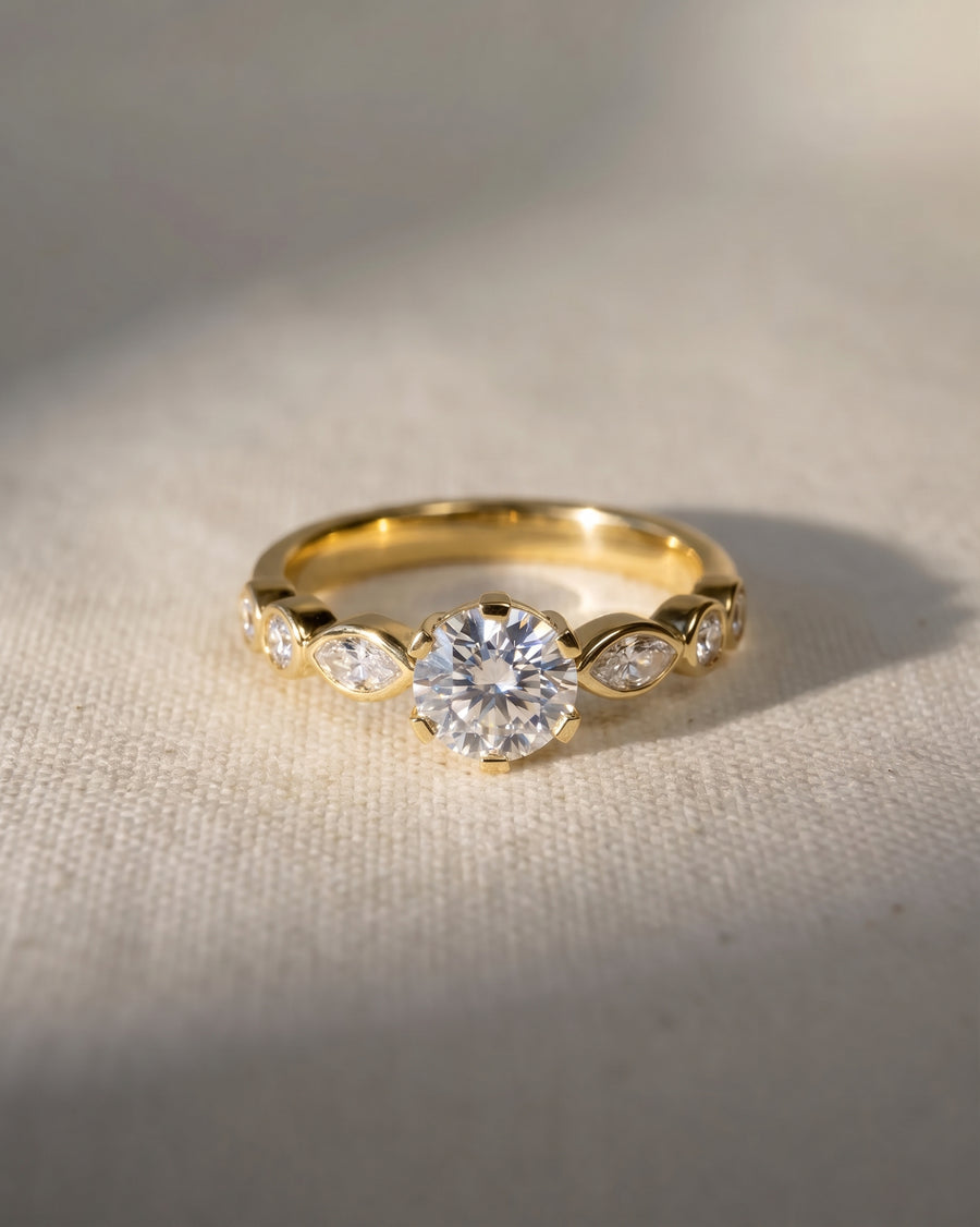 Gold engagement ring with a round cut diamond and marquise side stones.