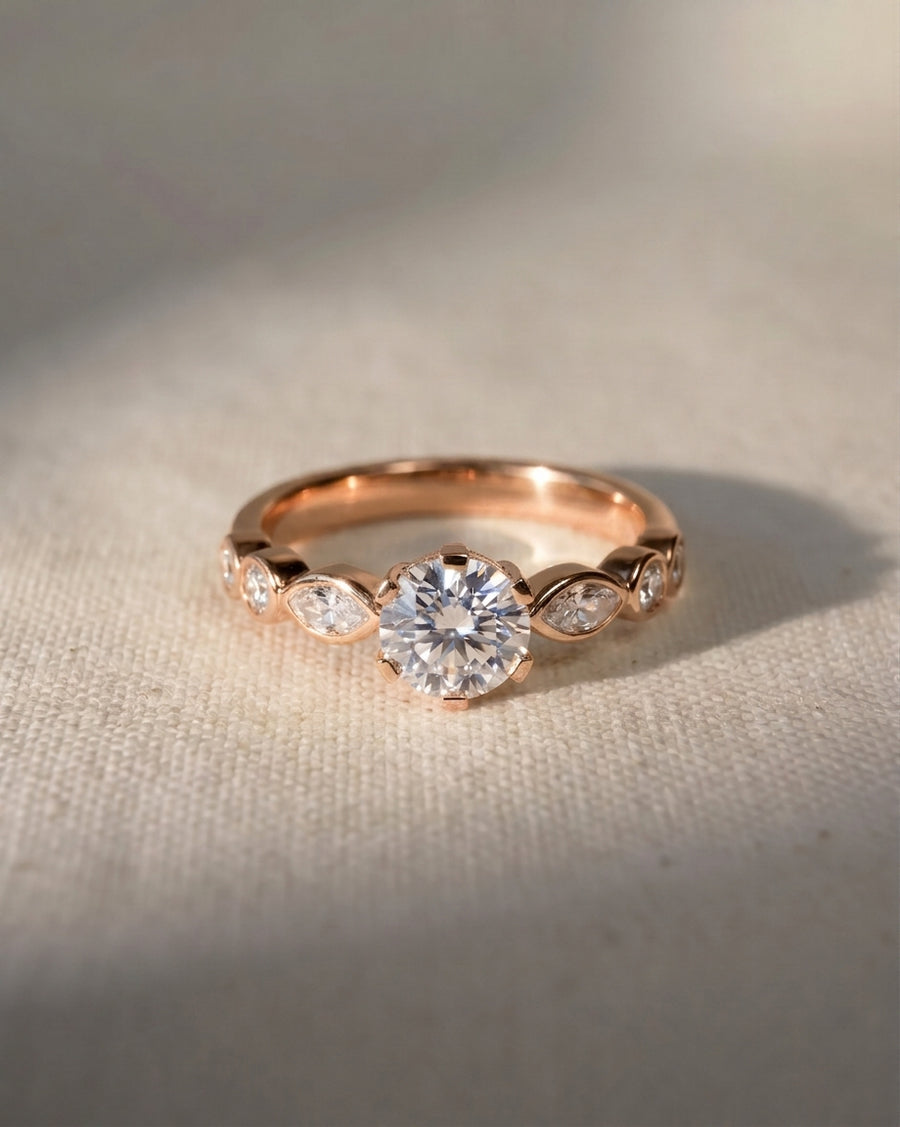 Rose gold engagement ring with a round cut center diamond and marquise side stones.