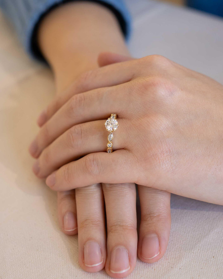 Gold engagement ring with a round cut diamond and smaller accent diamonds.