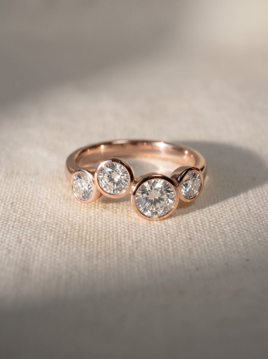 Rose gold ring with four bezel-set round diamonds arranged in a staggered bubble design.