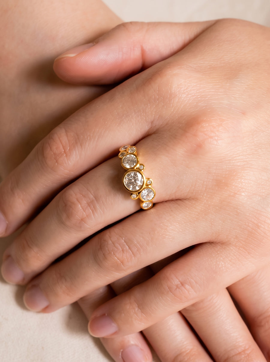 Gold ring with round cut diamonds in a bubble cluster design worn on a finger.