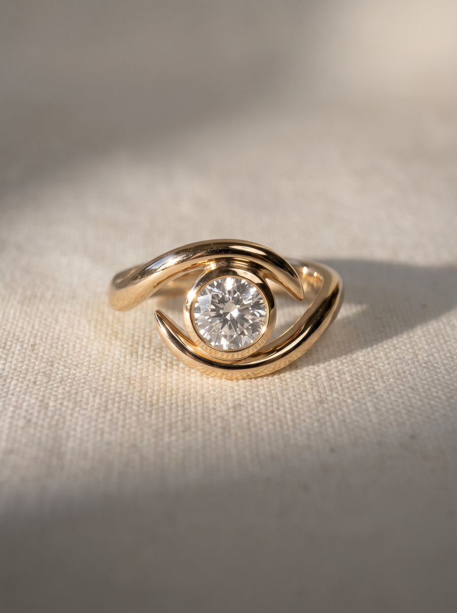 Gold engagement ring with a round cut diamond in a bezel setting and a curved, spiky band design.