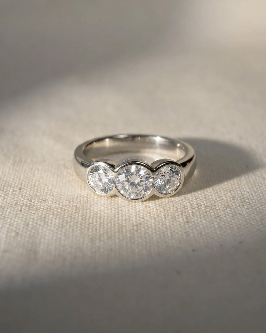 Silver round cut trilogy engagement ring with three diamonds.