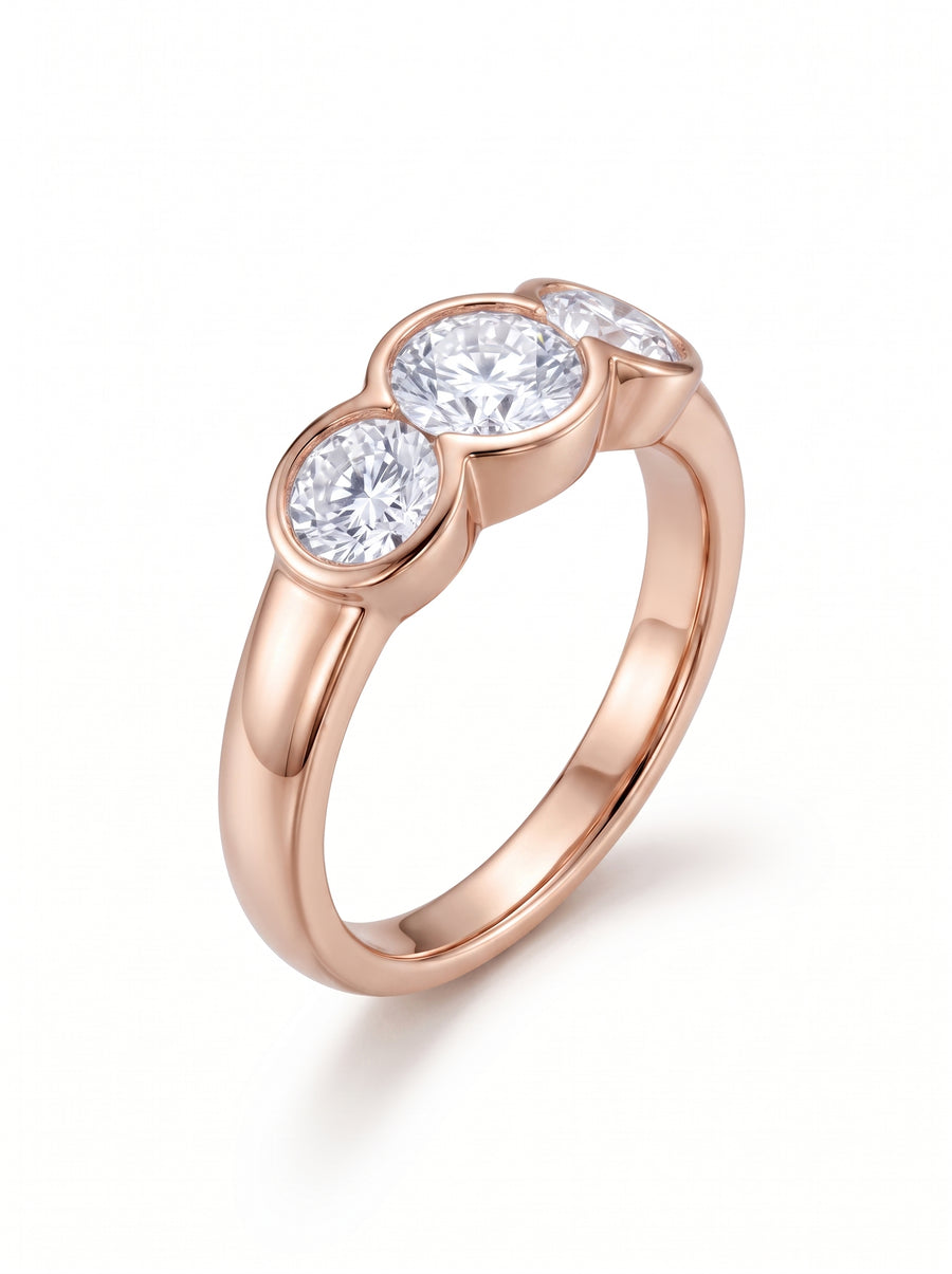 Trilogy engagement ring with three round cut diamonds in a rose gold bezel setting.