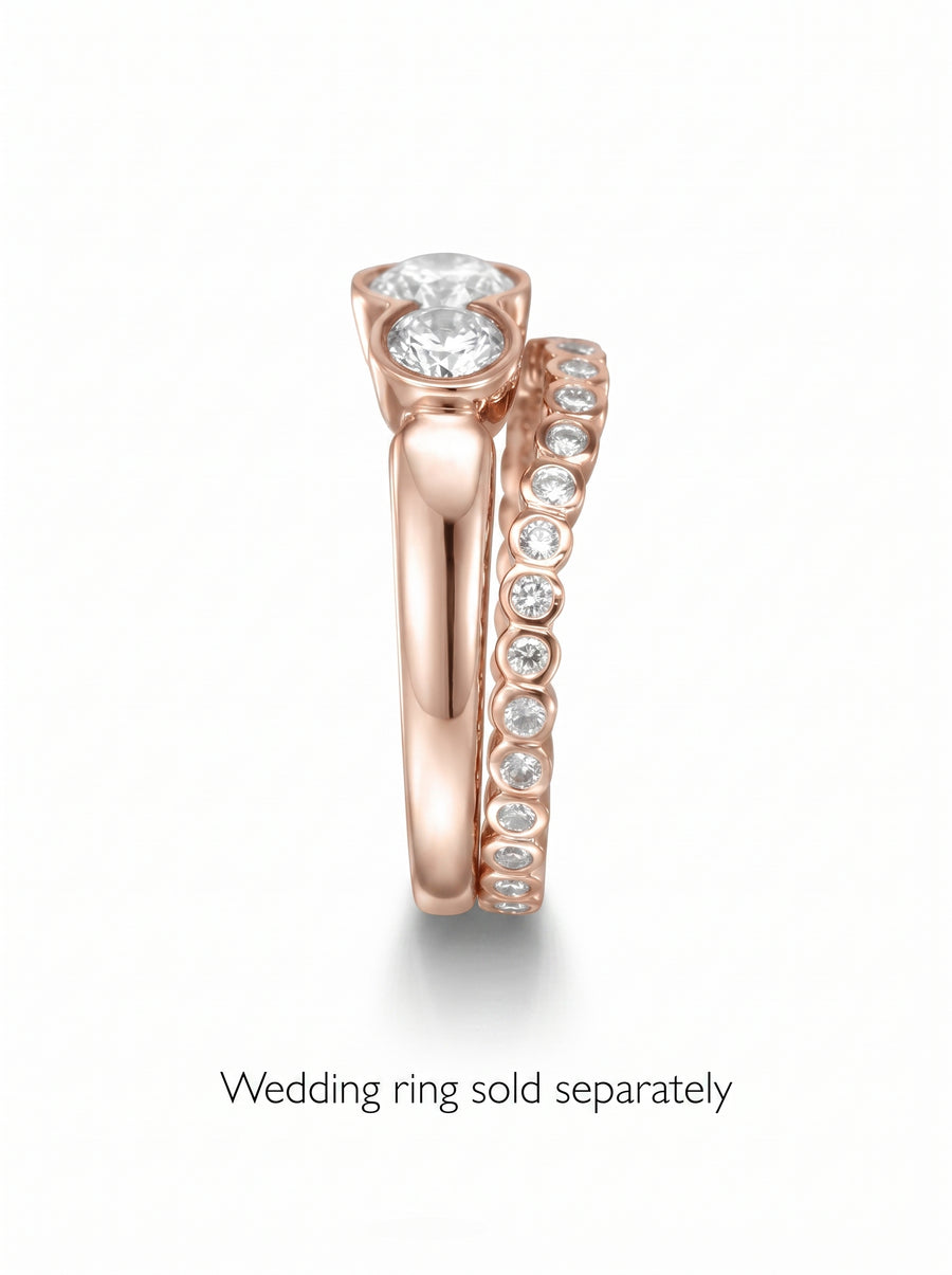 Rose gold trilogy engagement ring with three round cut diamonds paired with a diamond eternity wedding band.