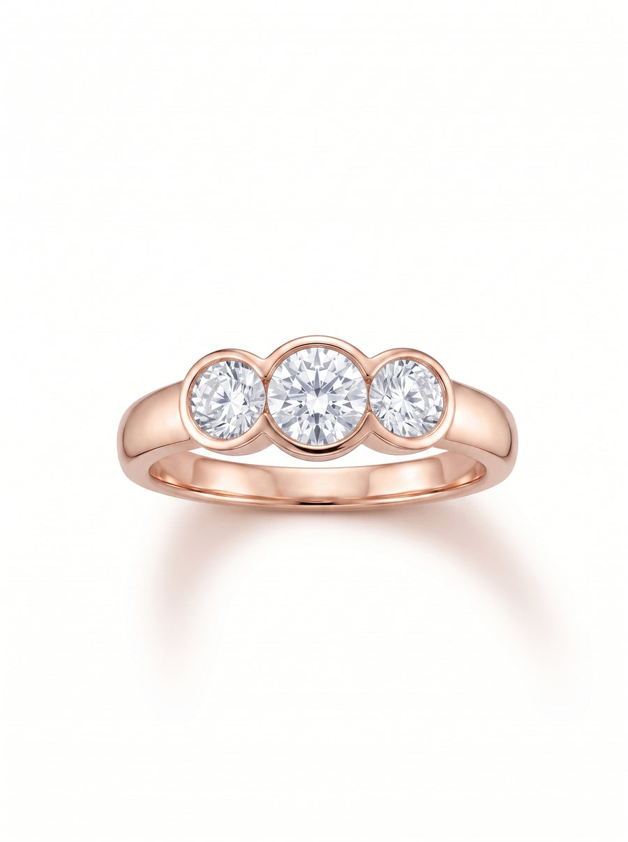 Trilogy engagement ring with three round cut diamonds in a rose gold bezel setting.