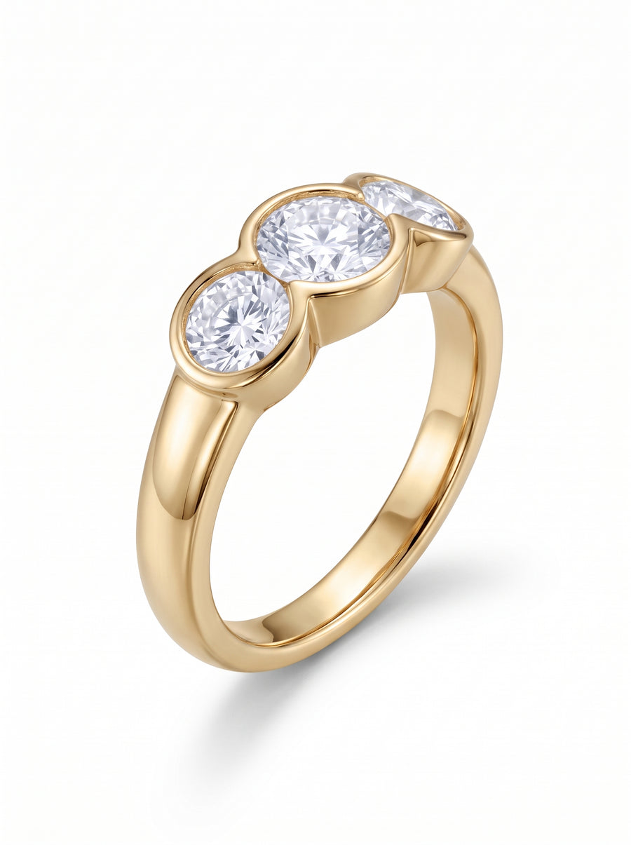 Gold trilogy engagement ring featuring three bezel-set round cut diamonds on a polished yellow gold band.