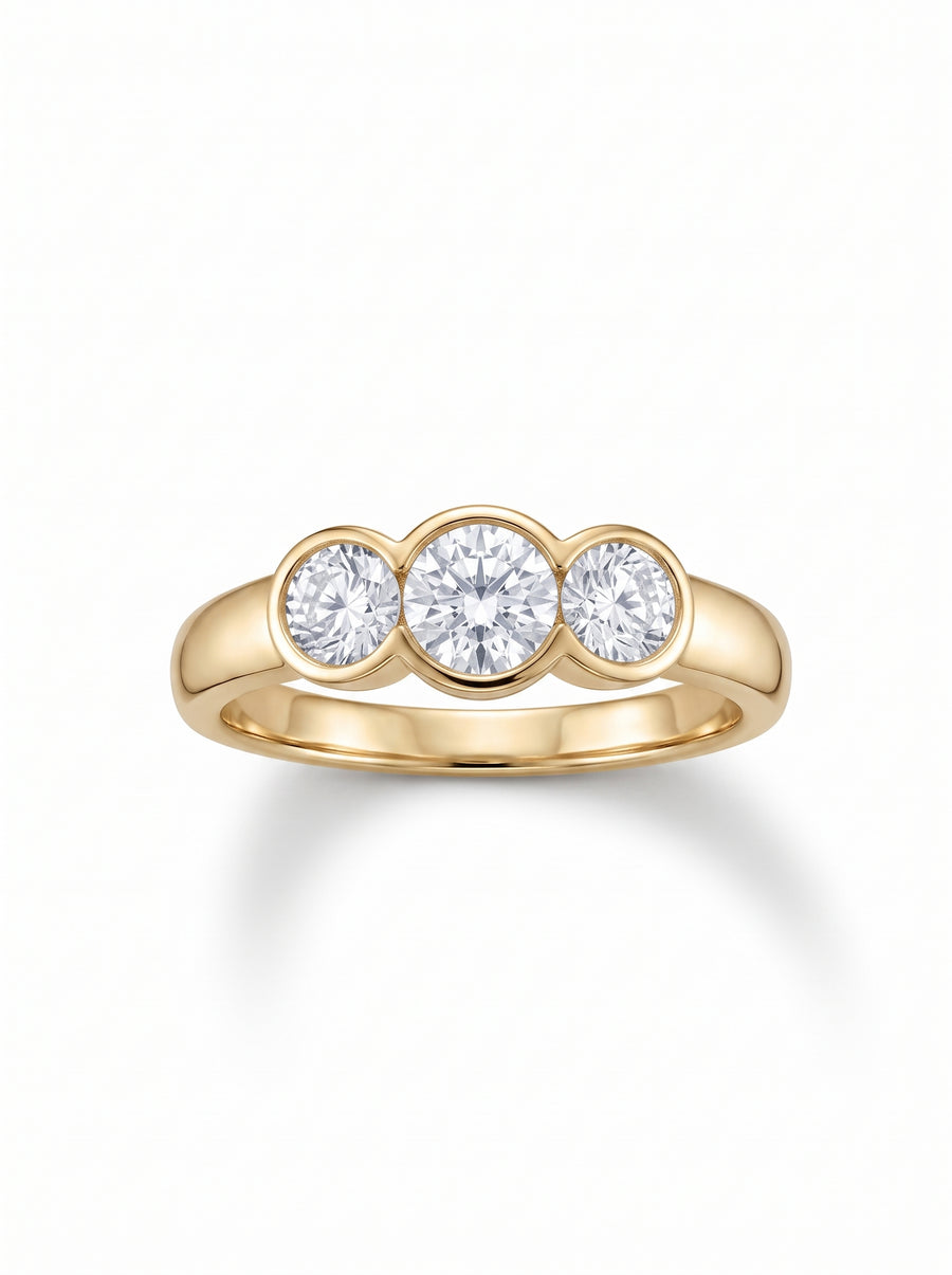 Trilogy engagement ring with three round cut diamonds in a yellow gold bezel setting.