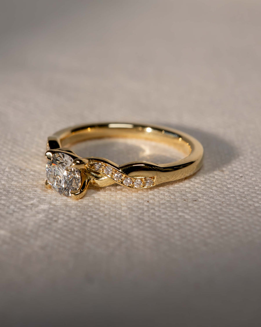 Gold round cut diamond engagement ring with a twist claw design.