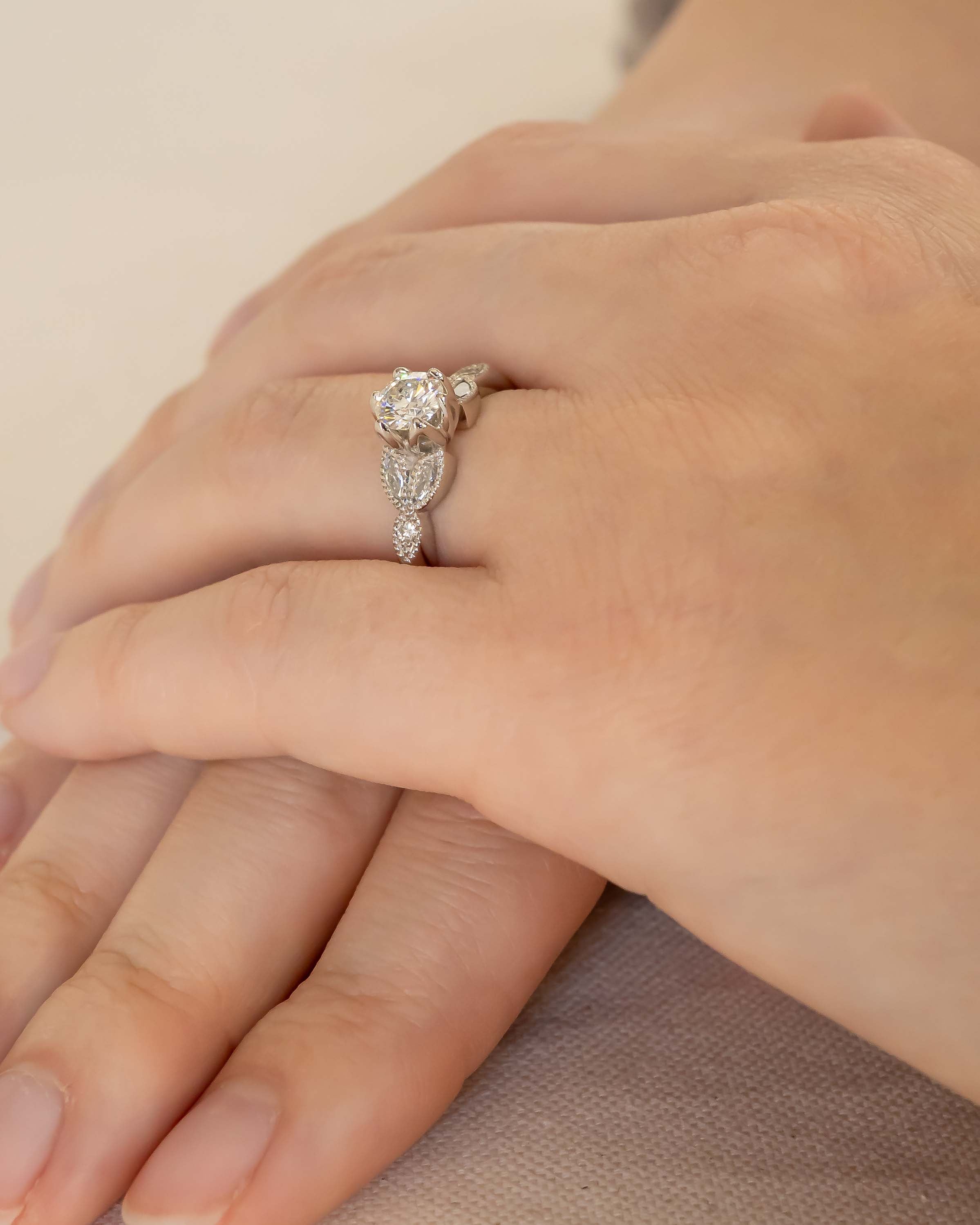 Silver round cut vintage engagement ring with diamonds on a hand.