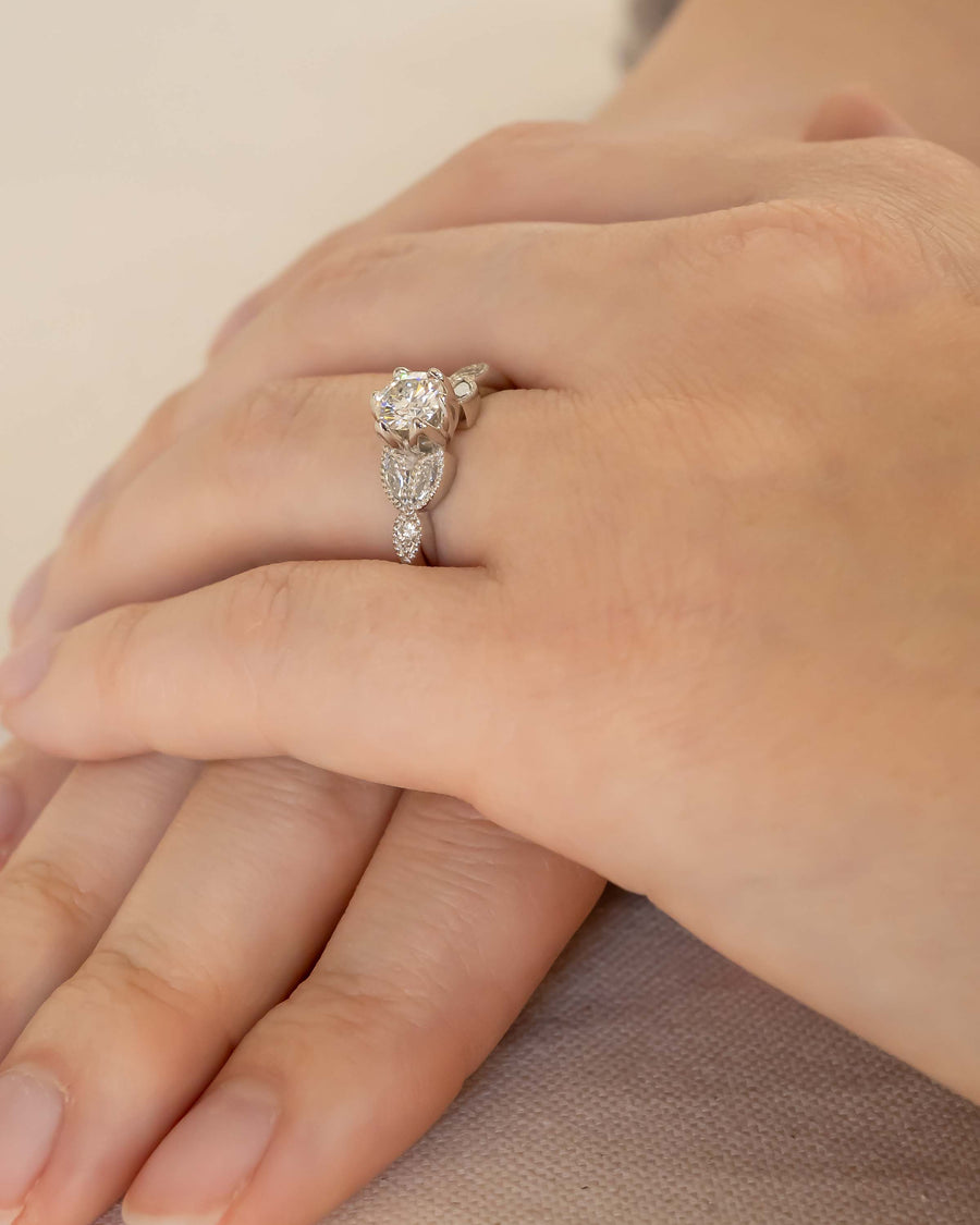 Silver round cut vintage engagement ring with diamonds on a hand.