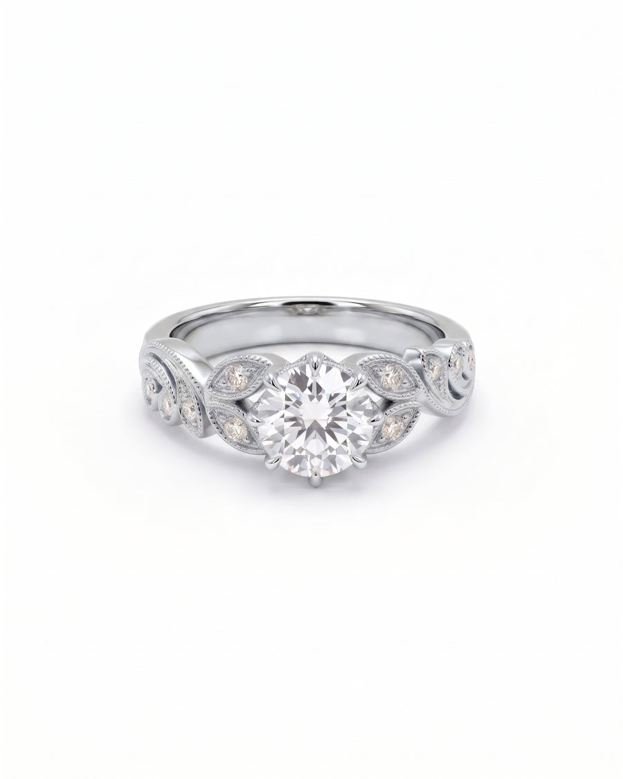 Round cut diamond engagement ring in platinum with leaf-inspired filigree and pavé accents.