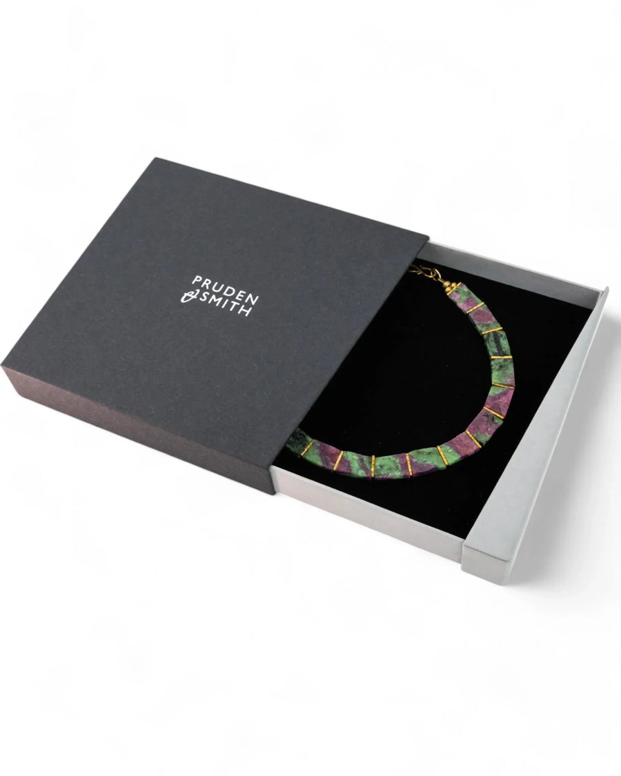 Ruby zoisite collar necklace with gold accents in a black gift box on white background