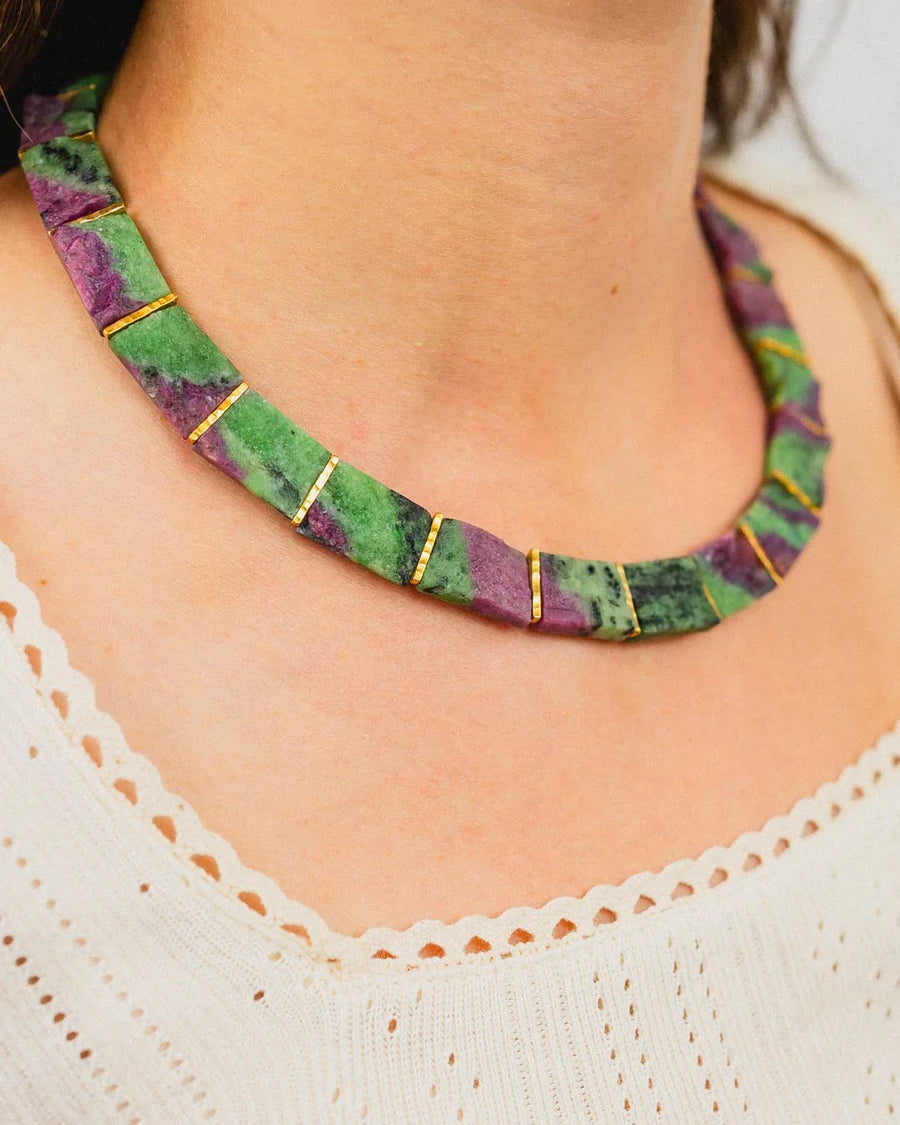 Ruby zoisite collar necklace with gold accents on a woman's neck