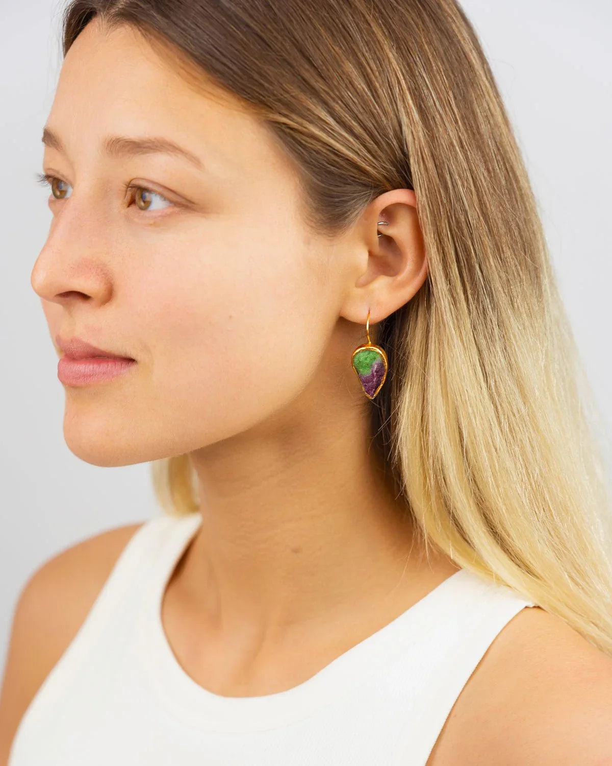 Woman wearing a gold drop earring with green and purple ruby zoisite stone