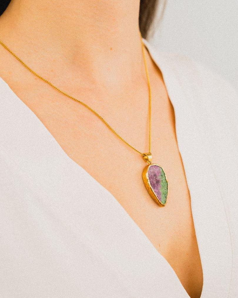 Gold chain necklace with natural ruby zoisite pendant worn on a woman's neck