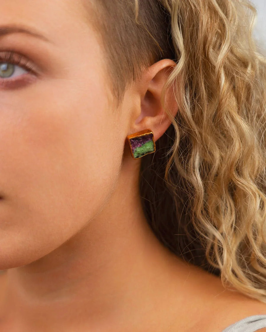 Woman wearing a square ruby zoisite stud earring with gold edge, close-up