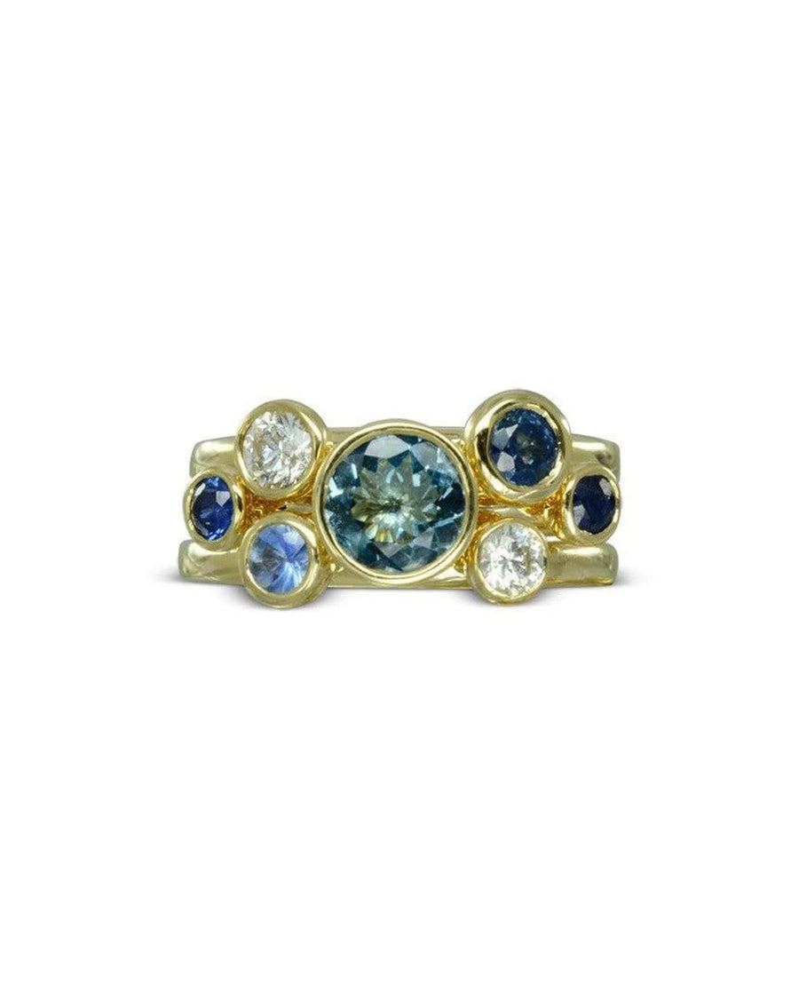 Gold stacking ring set with sapphire, aquamarine, and white gemstones in bezel settings.