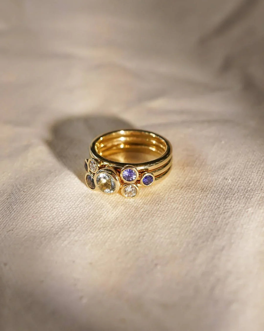 Gold stacking rings with sapphire, aquamarine, and diamond gemstones.