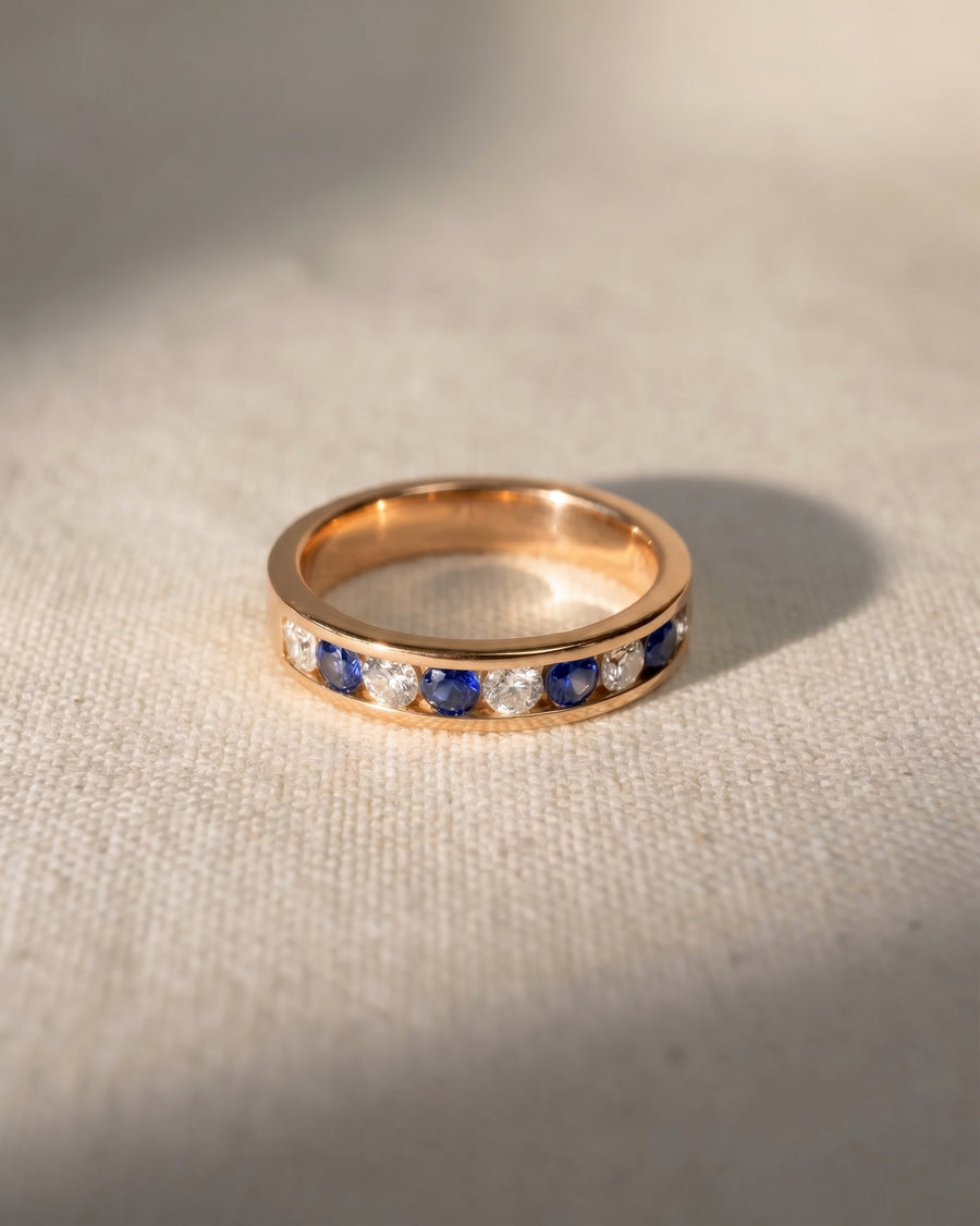 18ct rose gold eternity ring with alternating sapphire and diamond gemstones.