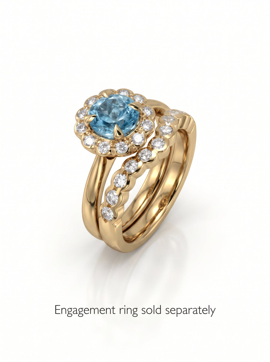 Gold scalloped wedding band featuring small round diamonds, shown stacked with a blue gemstone engagement ring.