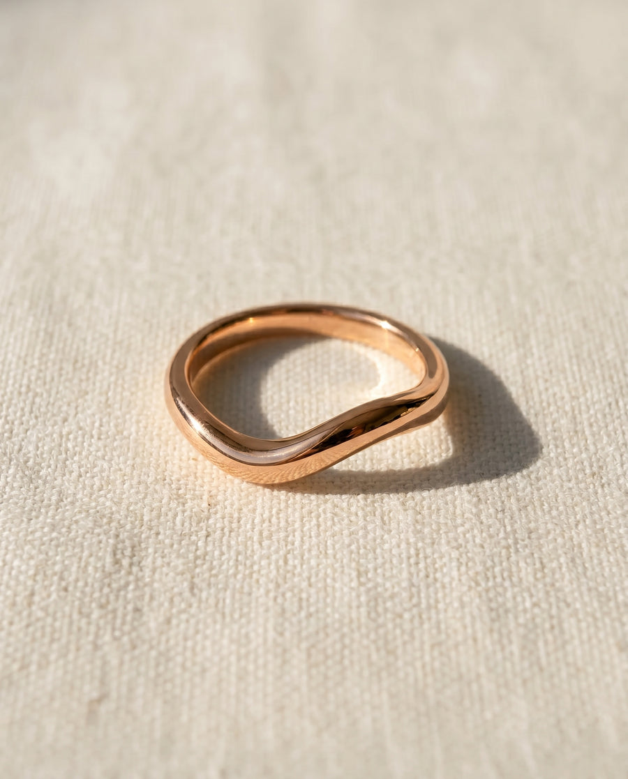 9ct rose gold 2mm shaped court wedding ring on a cream fabric.