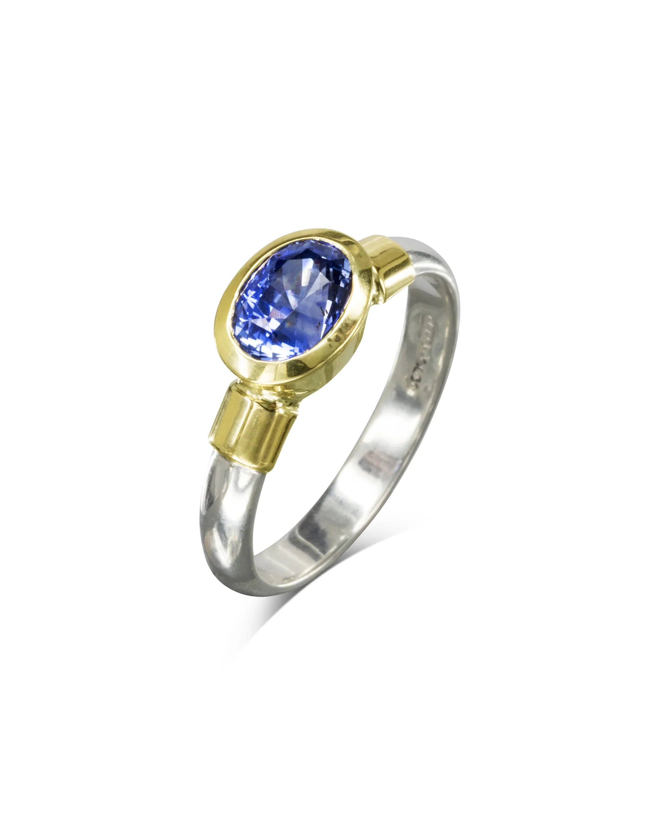 Handmade gold and silver ring with oval blue sapphire gemstone on white background