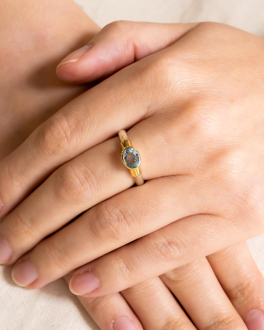 Gold and silver ring with an oval blue solitaire gemstone.