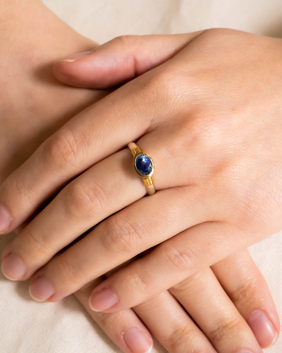 Gold and silver ring with an oval blue sapphire solitaire.