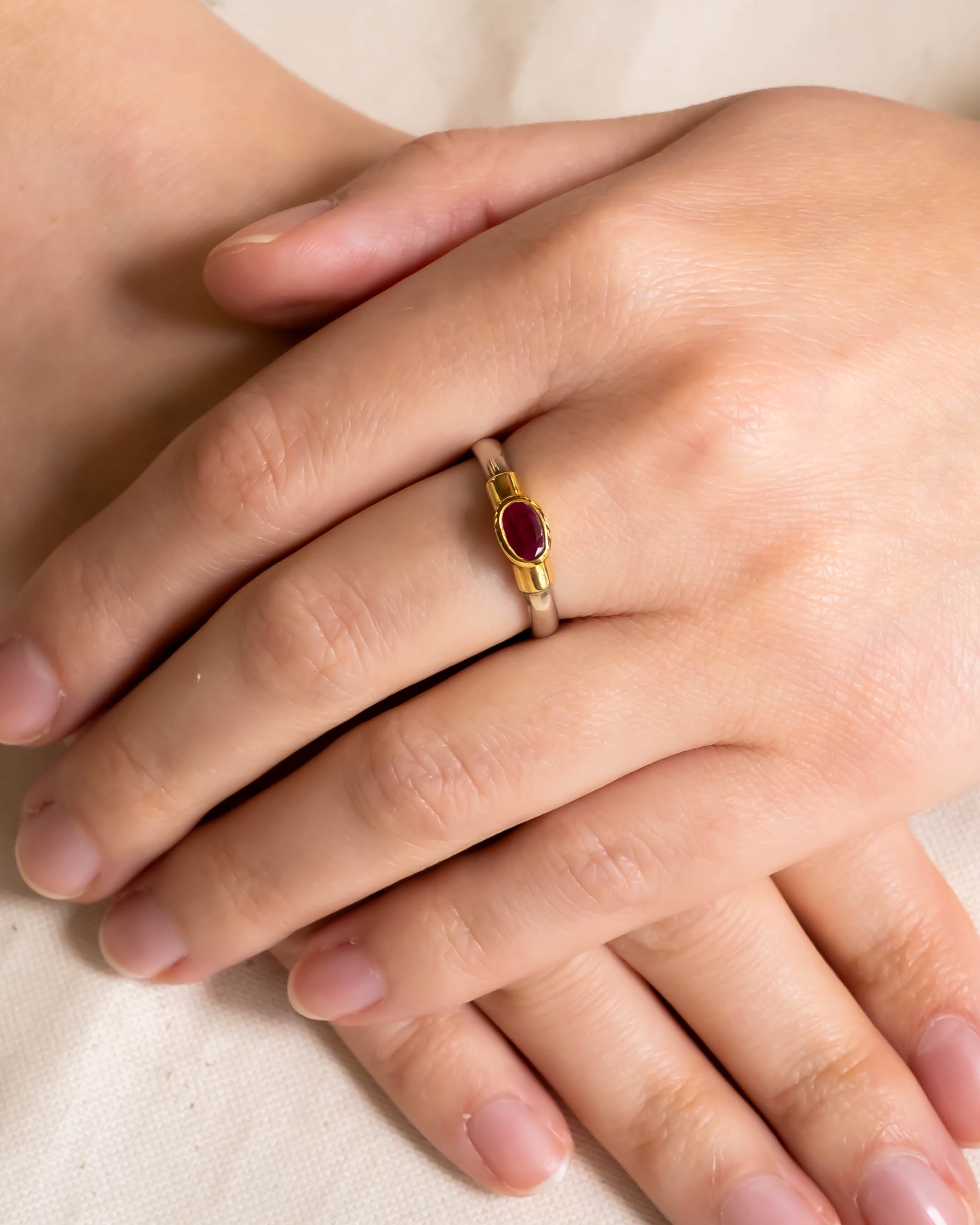 Two-tone shoulder ring with an oval ruby solitaire.