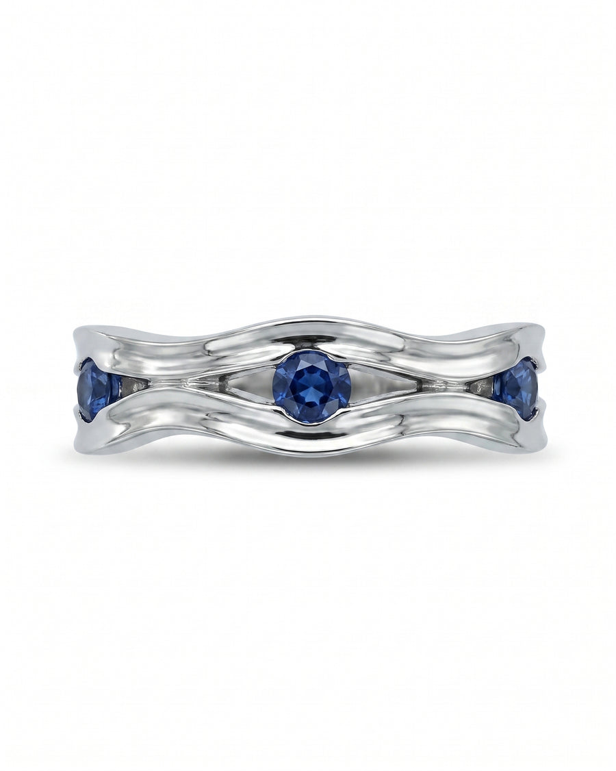Silver eternity ring with three round blue gemstones in a wavy, hammered design.