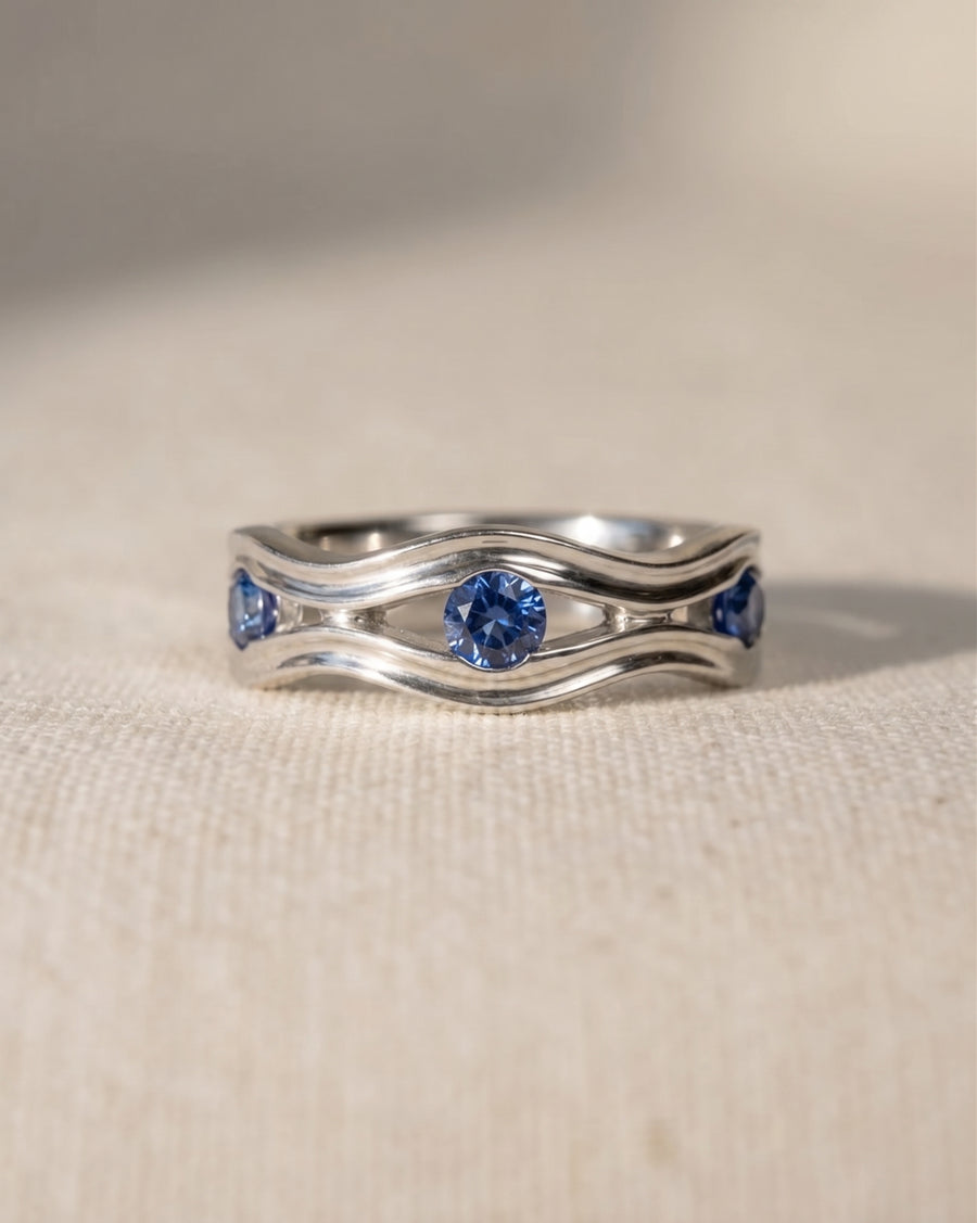 9ct white gold eternity ring with wavy bands and blue topaz gemstones.