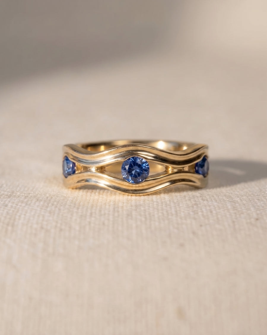 9ct yellow gold eternity ring with wavy side hammered design and blue topaz gemstones.