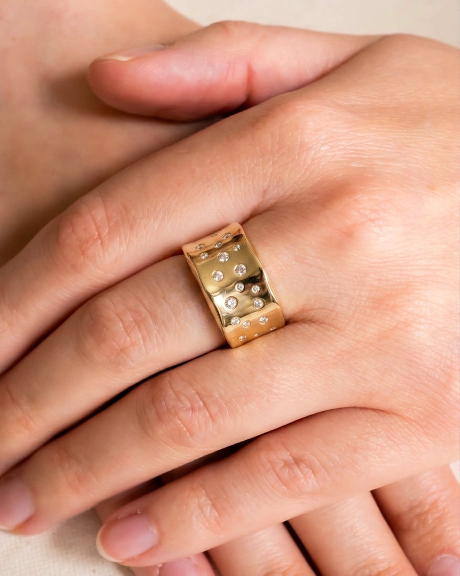 Wide gold eternity ring with scattered round diamonds.