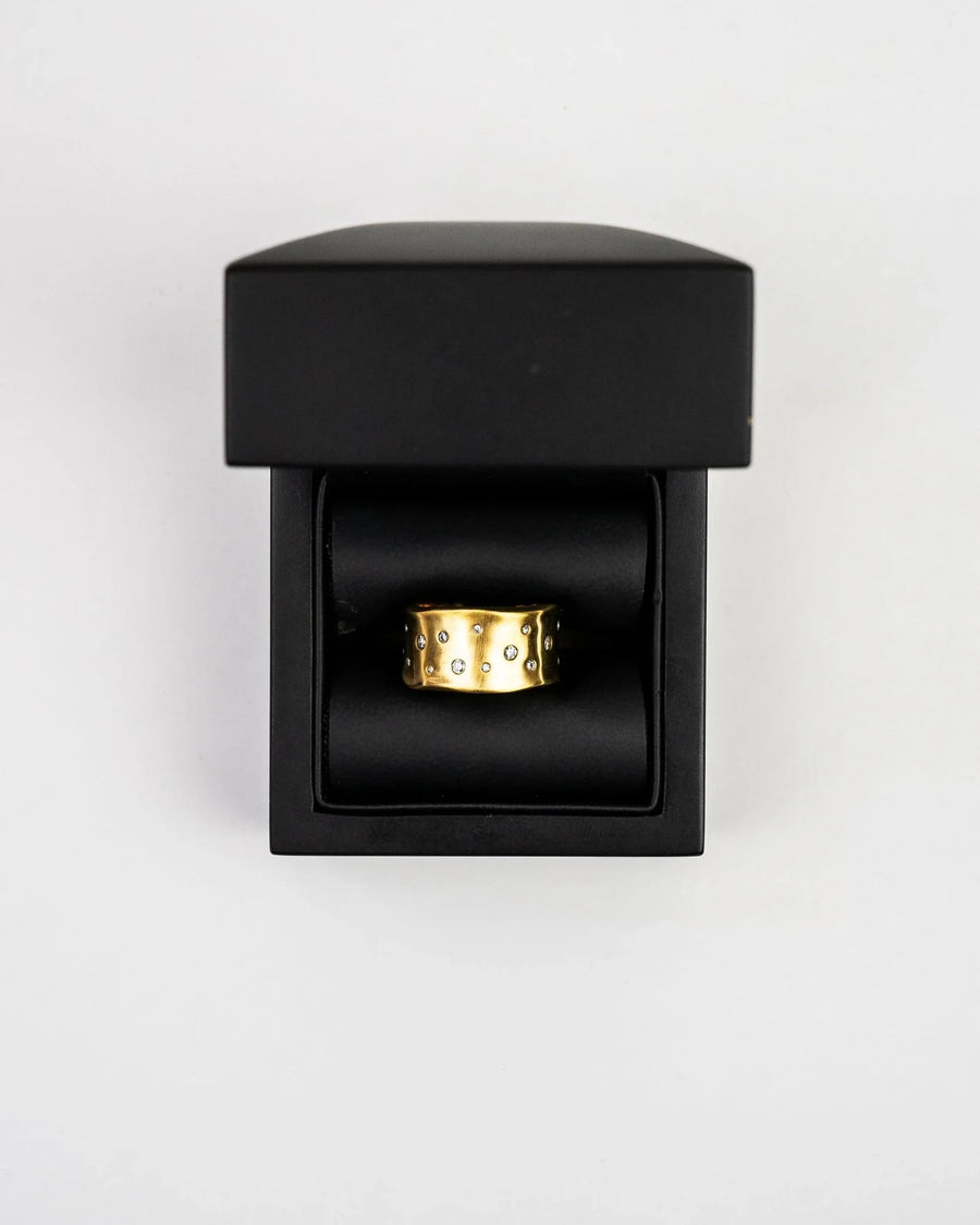Wide gold hammered brushed diamond eternity ring in a black box.