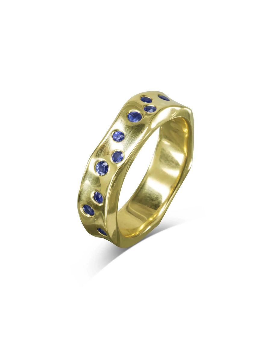 Gold eternity ring with side hammered texture and round blue gemstones.