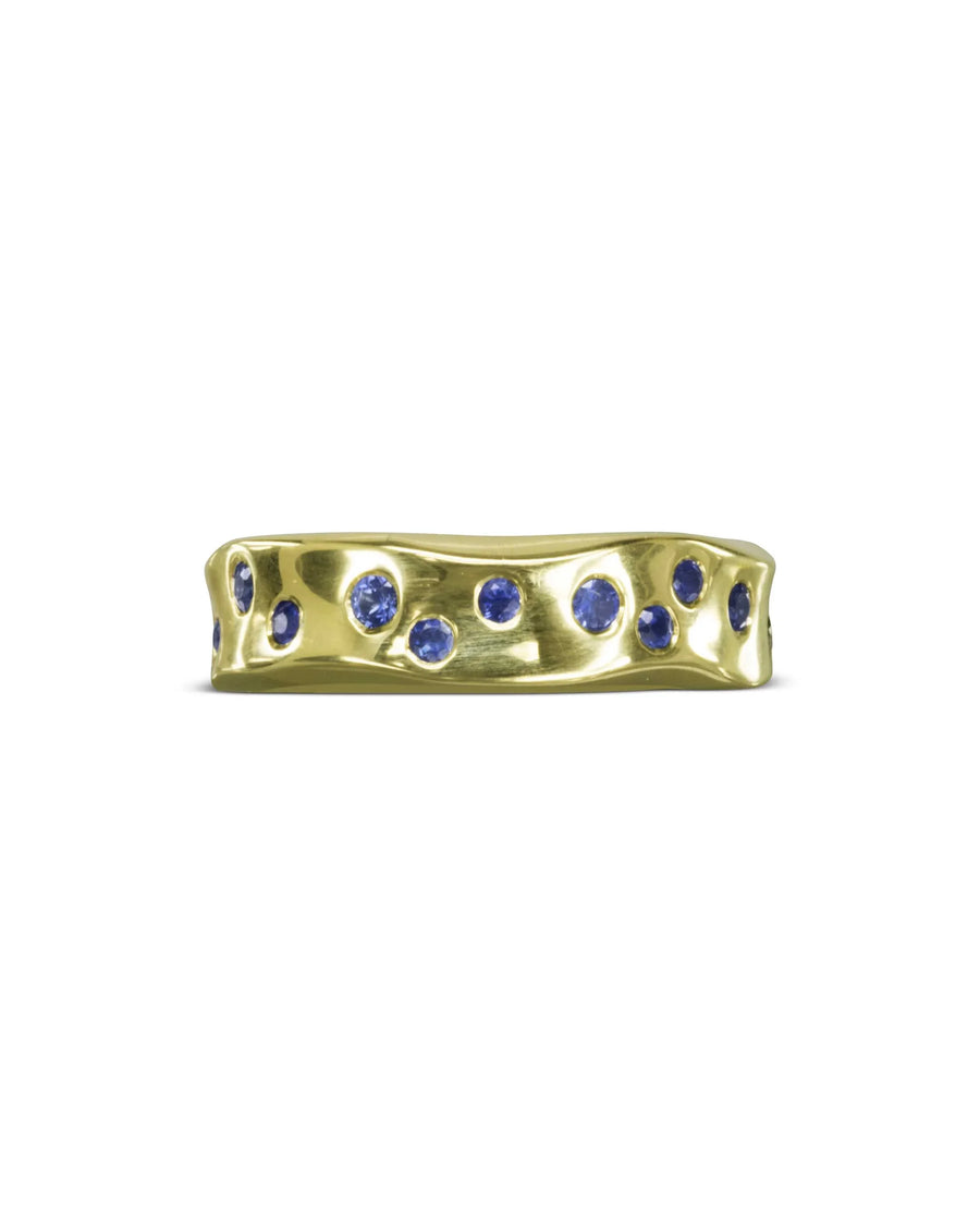 Gold hammered eternity ring with scattered blue gemstones.