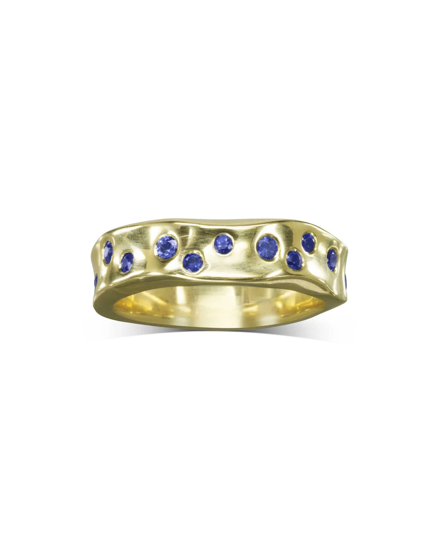 Gold side hammered eternity ring with round blue gemstones.