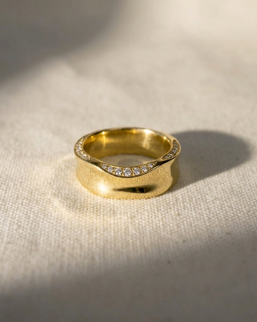 Gold eternity ring with hammered edge and diamond accents.
