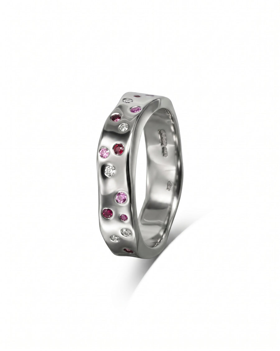 Silver hammered eternity ring with scattered ruby, pink sapphire, and diamond gemstones.