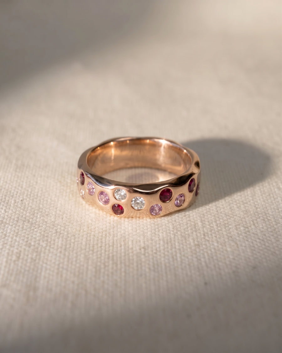 Rose gold eternity ring with ruby, pink sapphire, and diamond gemstones.