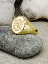 Gold engraved signet ring with stone background