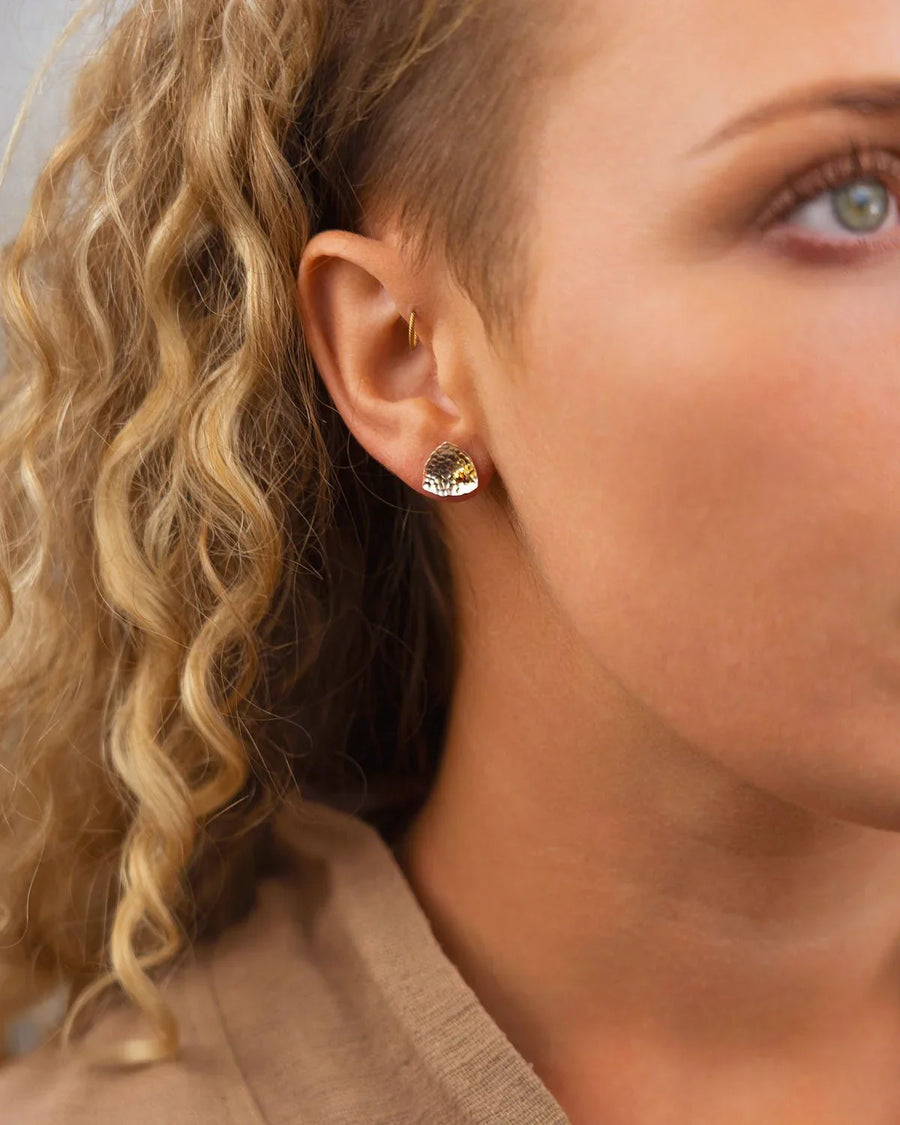 Silver and gold beaded stud earring on an ear.